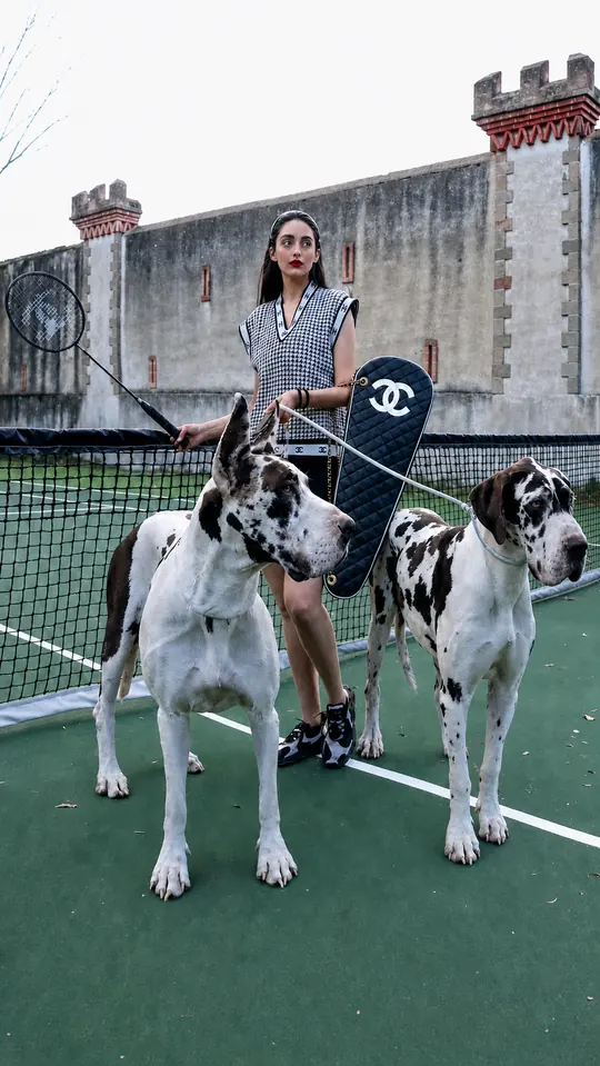 Liz con dos grandes daneses en una cancha de tenis